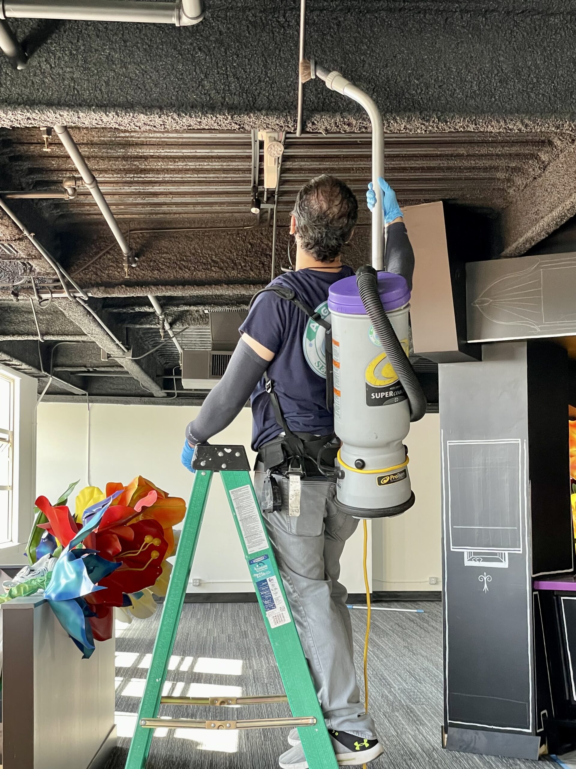 Professional worker using a duster to clean high surfaces in a commercial building