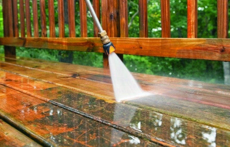 Professional power washing team cleaning a dirty sidewalk with high-pressure water.