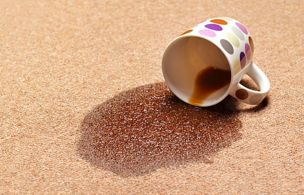 Dark coffee stain on a beige carpet.