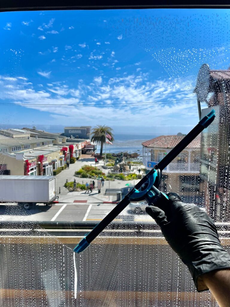 Janitor securely harnessed, cleaning high-rise office windows, janitorial services description 